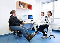Judith Lohse (r), Kinderärztin, und Katharina Egger-Heidrich, Fachärztin Onkologie, sitzen mit einer Patientin im Nationalen Centrum für Tumorerkrankungen in einem Behandlungsraum.